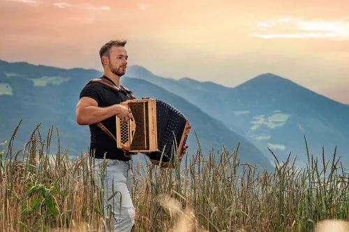 Harmonicademy Abo-Modell: Musiker spielt Steirische Harmonika in den Bergen